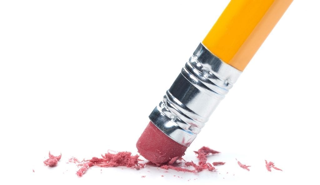 A pencil eraser removing a written mistake on a piece of paper.