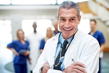 Portrait of cheerful doctor in a hospital standing with arms crossed.