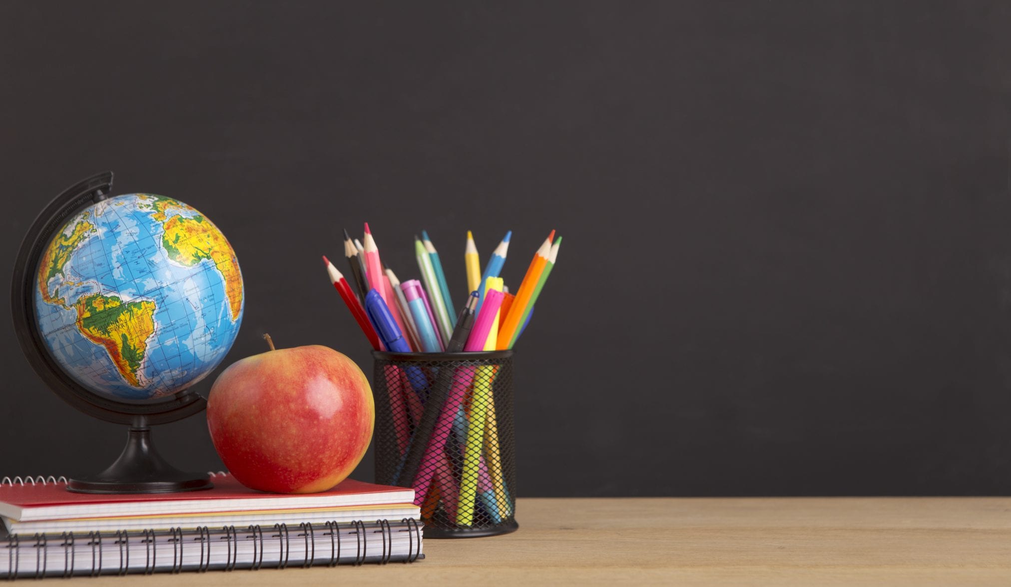 Stationery, world globe and apple over black board