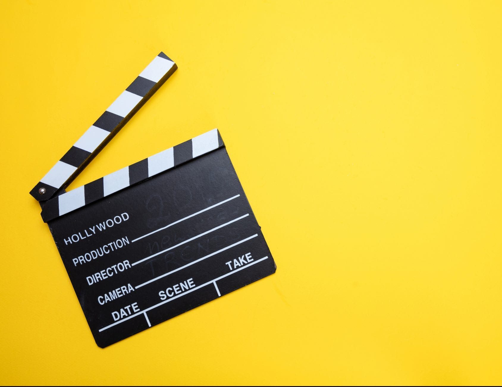 Movie clapperboard on yellow color background, top view